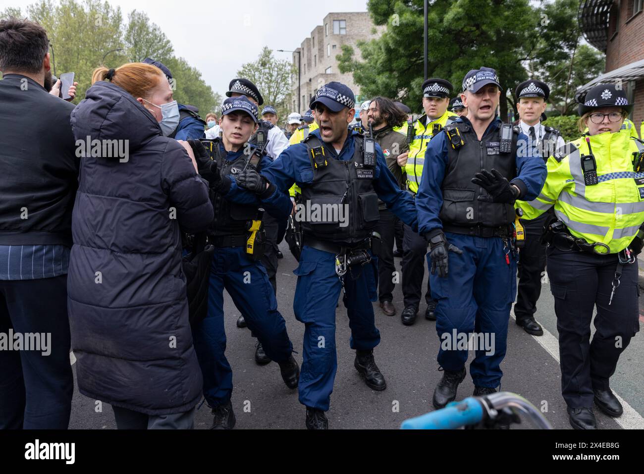 A coach sent to collect asylum seekers and take them to the Bibby Stockholm barge surrounded by protesters in Peckham south London England, UK Stock Photo