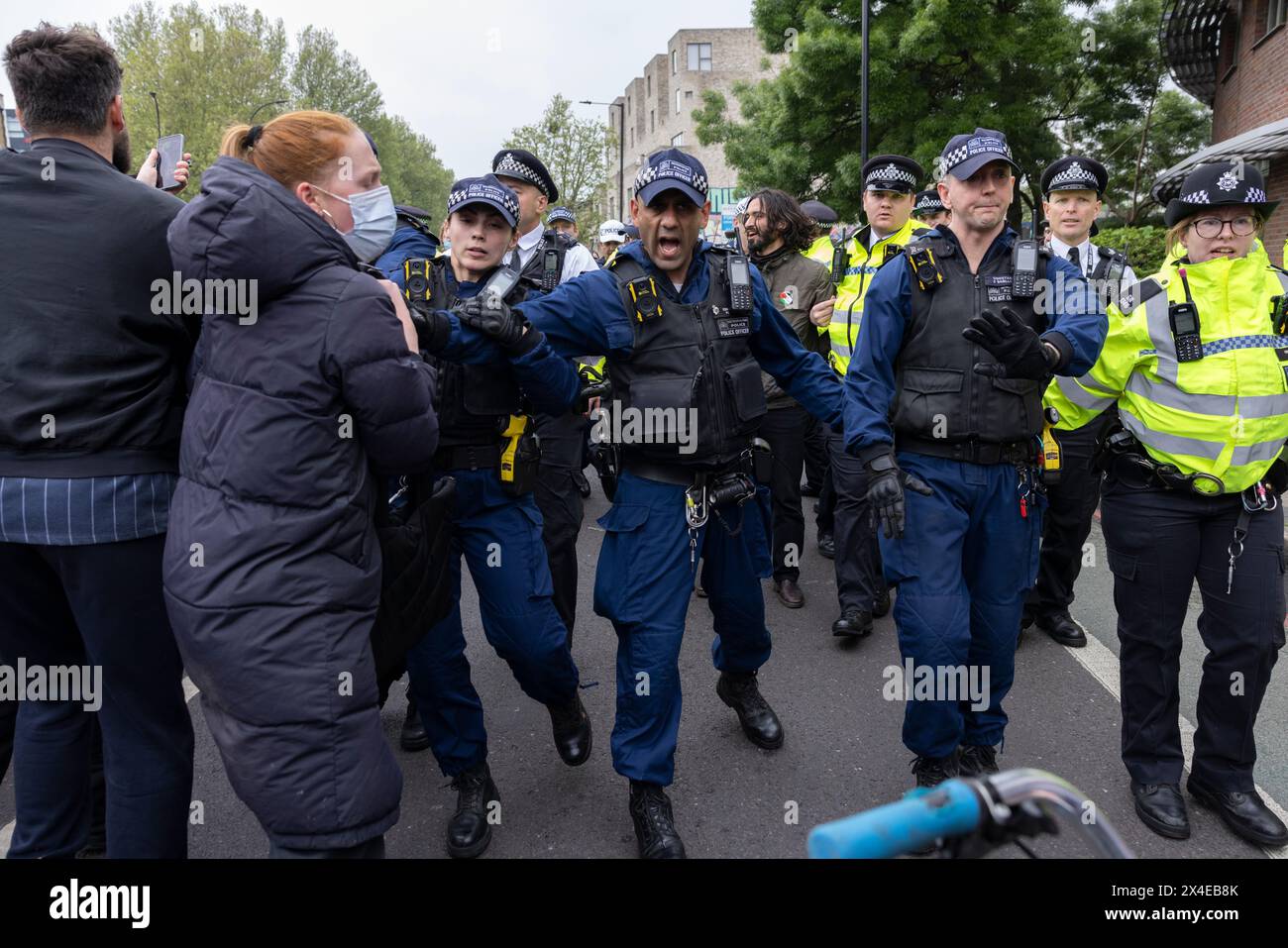 A coach sent to collect asylum seekers and take them to the Bibby Stockholm barge surrounded by protesters in Peckham south London England, UK Stock Photo