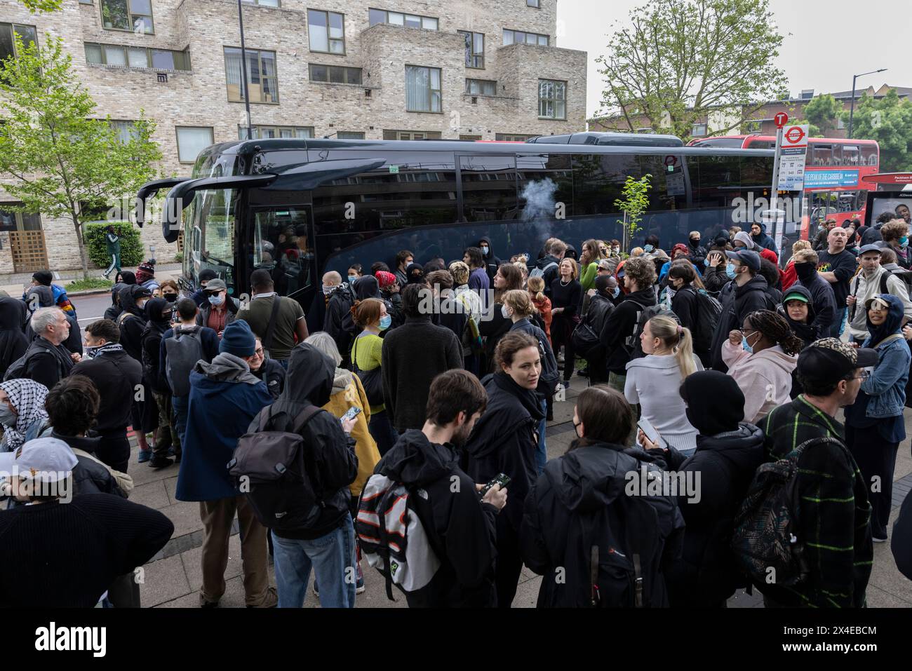 A coach sent to collect asylum seekers and take them to the Bibby Stockholm barge surrounded by protesters in Peckham south London England, UK Stock Photo