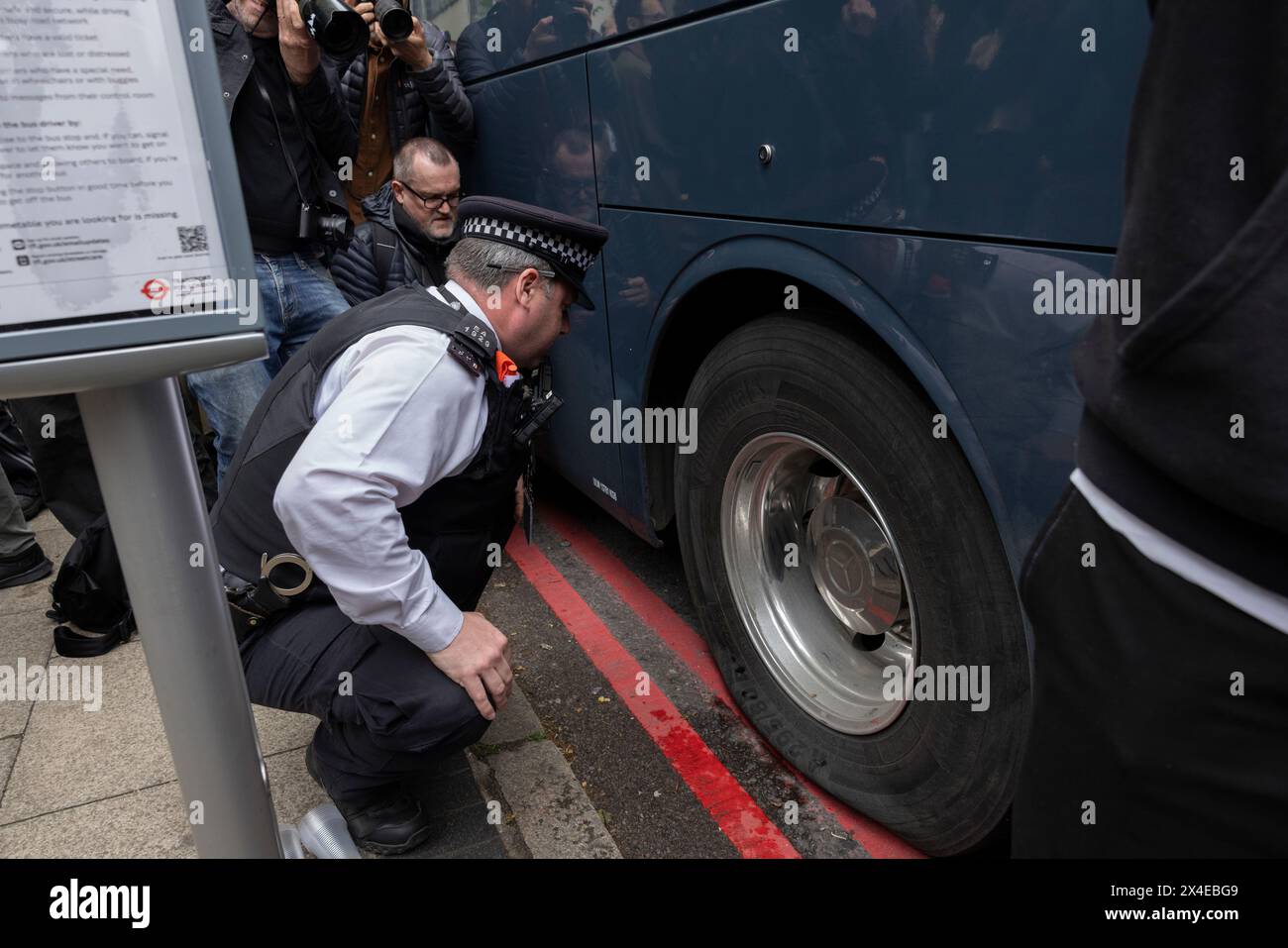 A coach sent to collect asylum seekers and take them to the Bibby Stockholm barge surrounded by protesters in Peckham south London England, UK Stock Photo