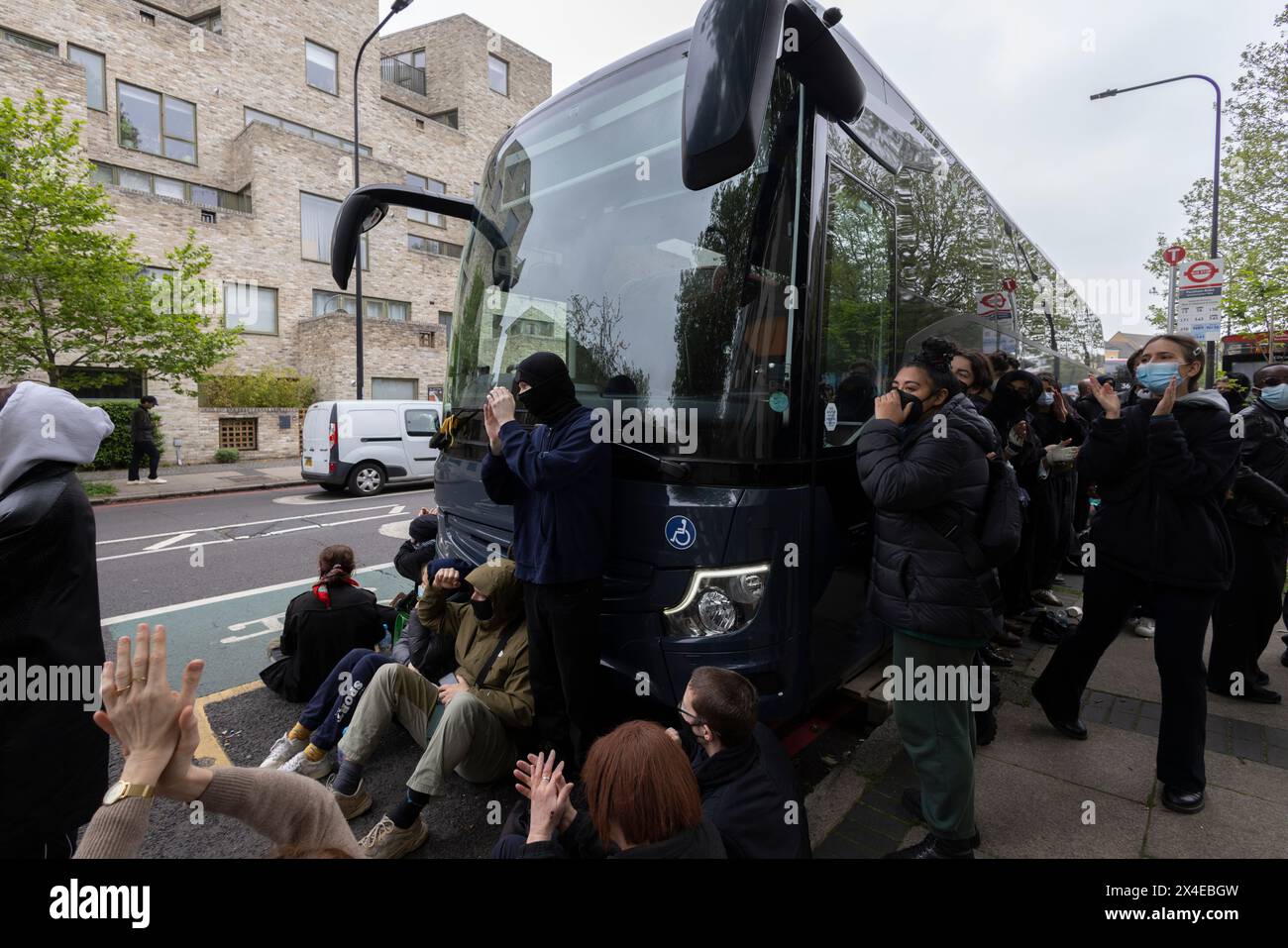 A coach sent to collect asylum seekers and take them to the Bibby Stockholm barge surrounded by protesters in Peckham south London England, UK Stock Photo