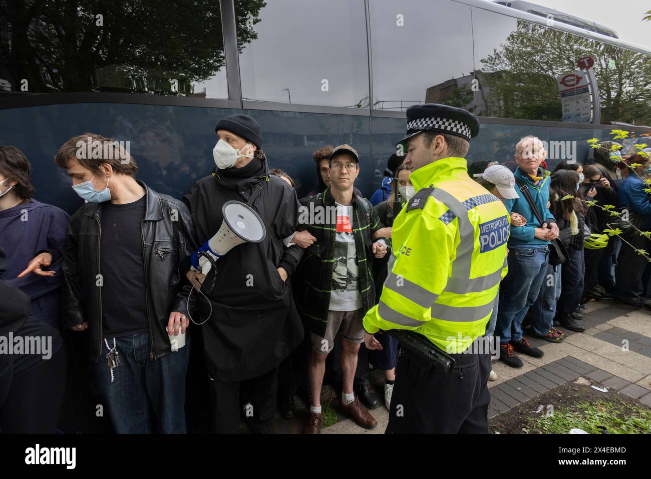 A coach sent to collect asylum seekers and take them to the Bibby Stockholm barge surrounded by protesters in Peckham south London England, UK Stock Photo