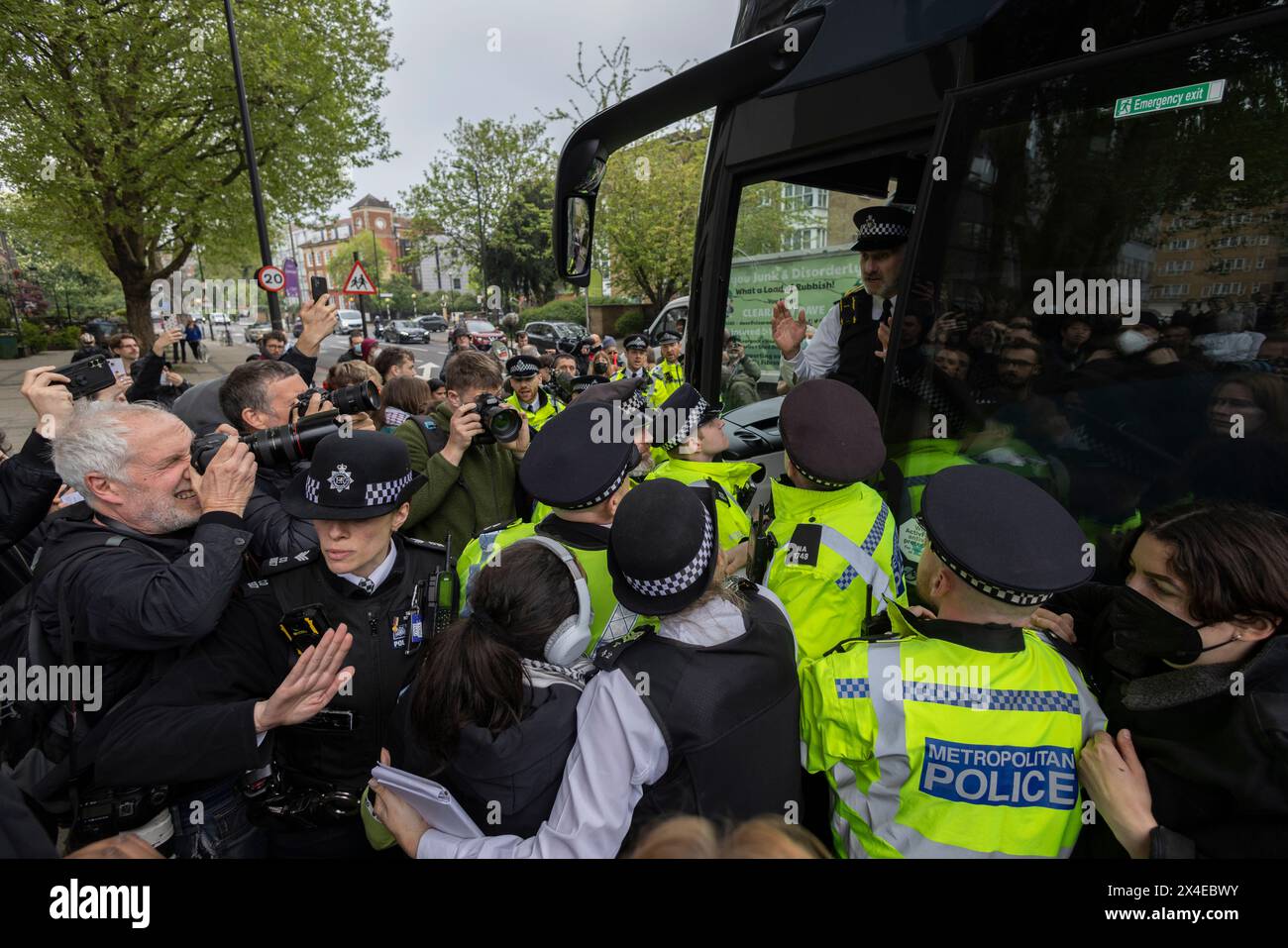 A coach sent to collect asylum seekers and take them to the Bibby Stockholm barge surrounded by protesters in Peckham south London England, UK Stock Photo