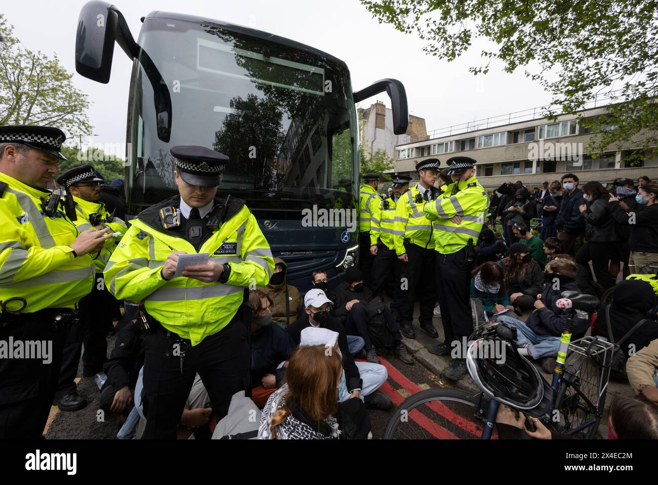 A coach sent to collect asylum seekers and take them to the Bibby Stockholm barge surrounded by protesters in Peckham south London England, UK Stock Photo