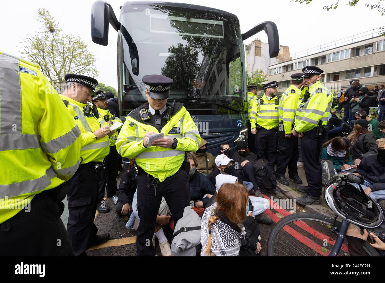 A coach sent to collect asylum seekers and take them to the Bibby Stockholm barge surrounded by protesters in Peckham south London England, UK Stock Photo