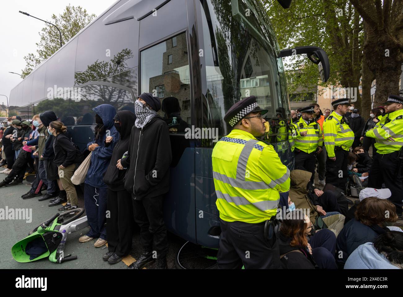 A coach sent to collect asylum seekers and take them to the Bibby Stockholm barge surrounded by protesters in Peckham south London England, UK Stock Photo