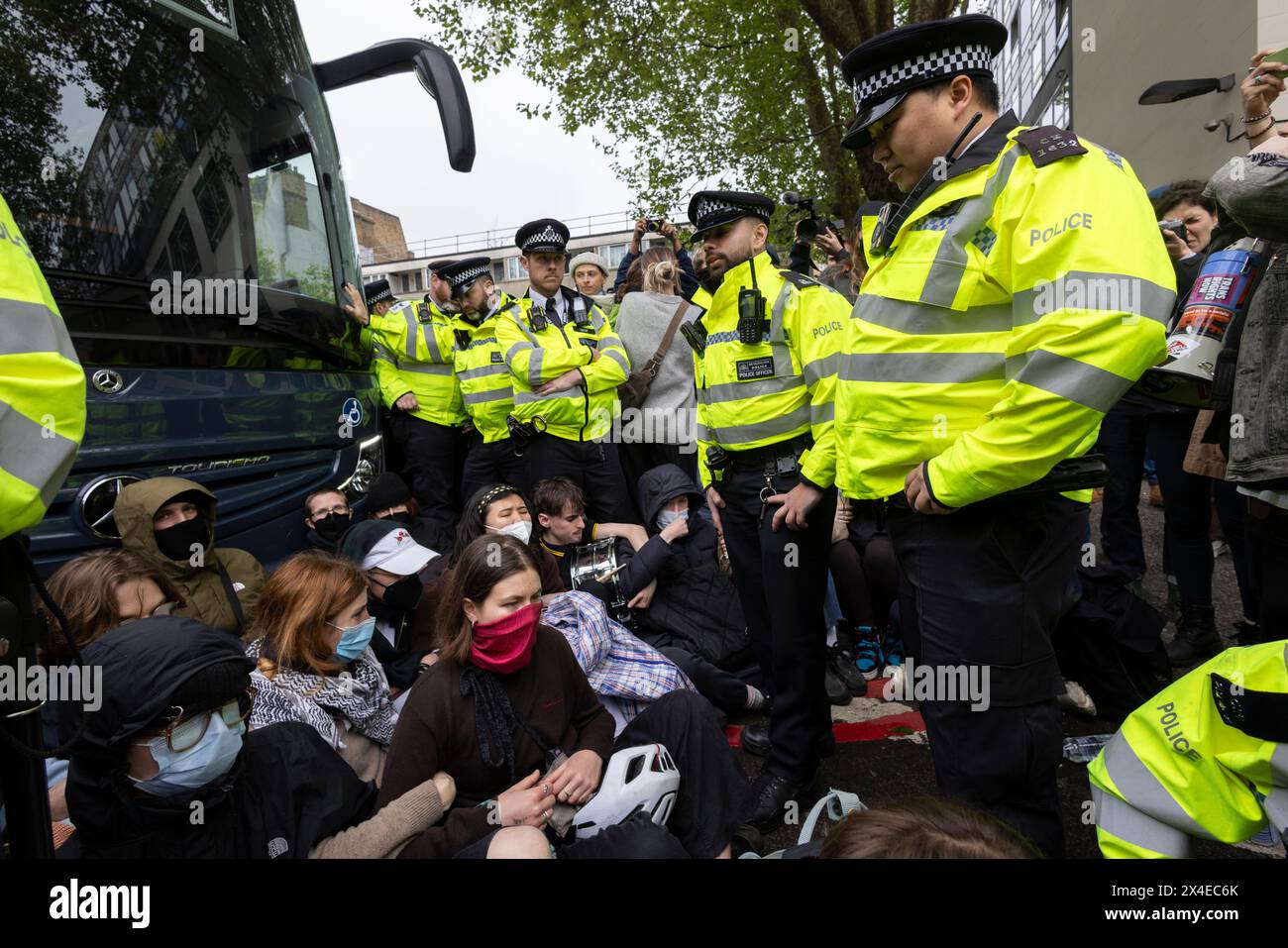 A coach sent to collect asylum seekers and take them to the Bibby Stockholm barge surrounded by protesters in Peckham south London England, UK Stock Photo