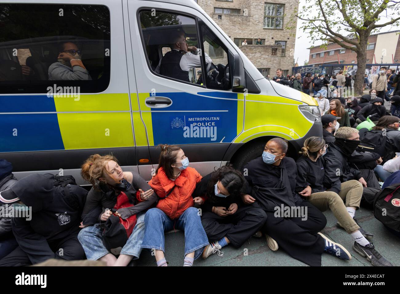 A coach sent to collect asylum seekers and take them to the Bibby Stockholm barge surrounded by protesters in Peckham south London England, UK Stock Photo