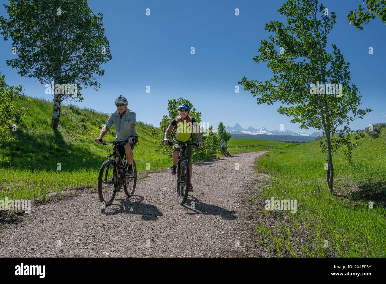 USA, Idaho. Couple cycling on trail near Tetonia. Teton Mountains in ...