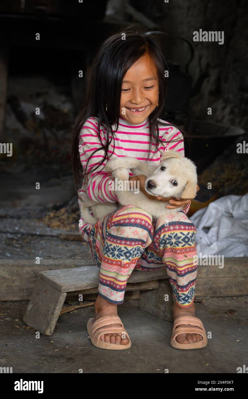 Young girl playing with a dog, Lao Cai Province, Vietnam Stock Photo