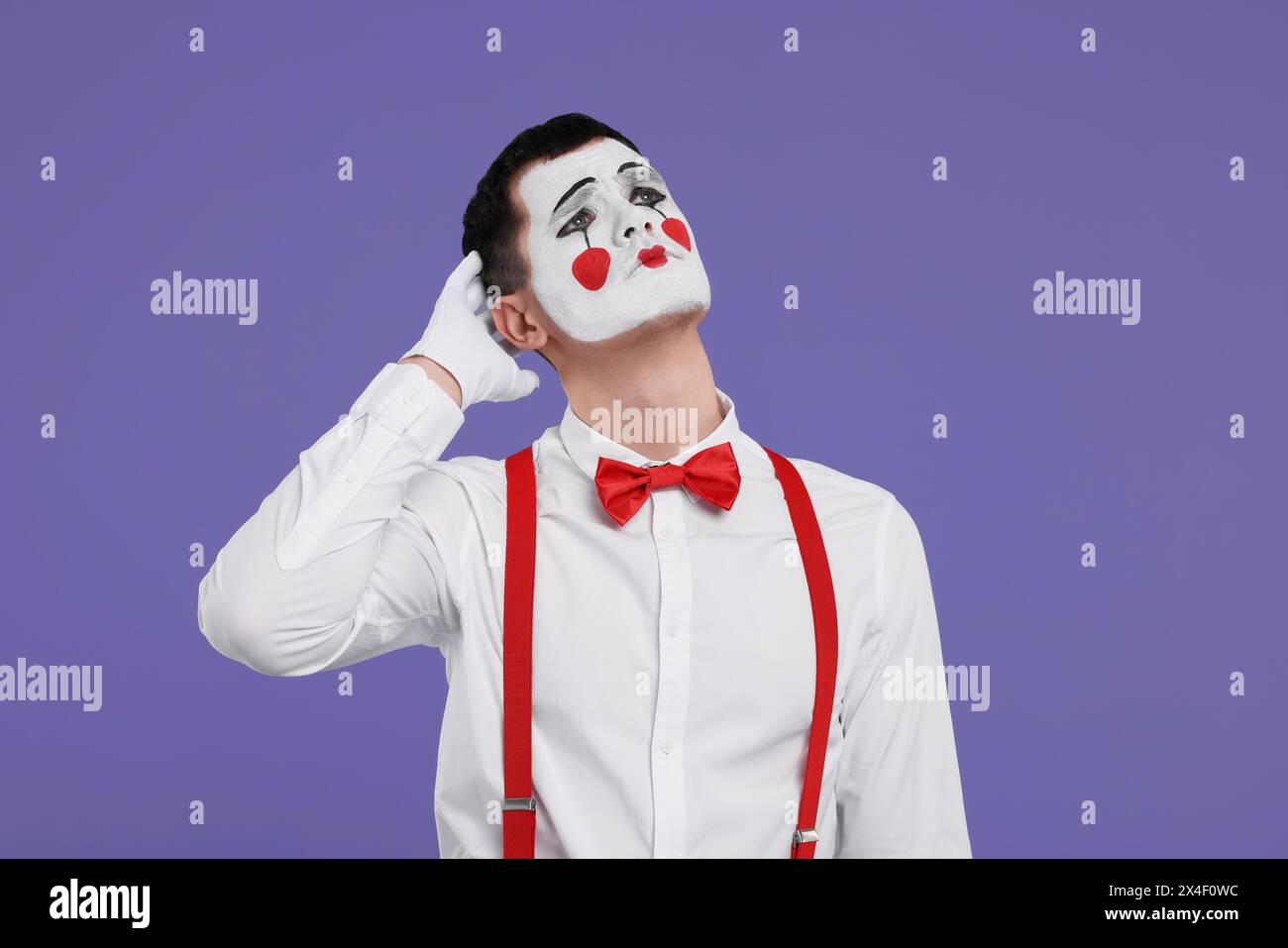 Mime artist making sad face on purple background Stock Photo