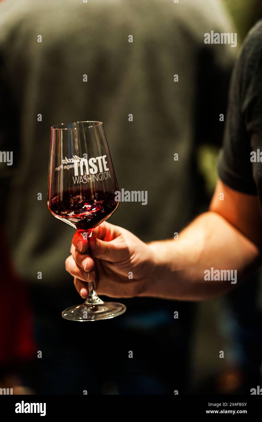 USA, Washington State, Seattle. Man holds glass of red wine at The Grand Tasting, a Taste Washington event. (Editorial Use Only) Stock Photo