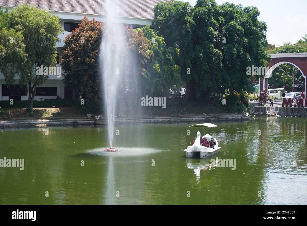 Several women ride a duck boat on an artificial lake with a fountain on a campus Stock Photo