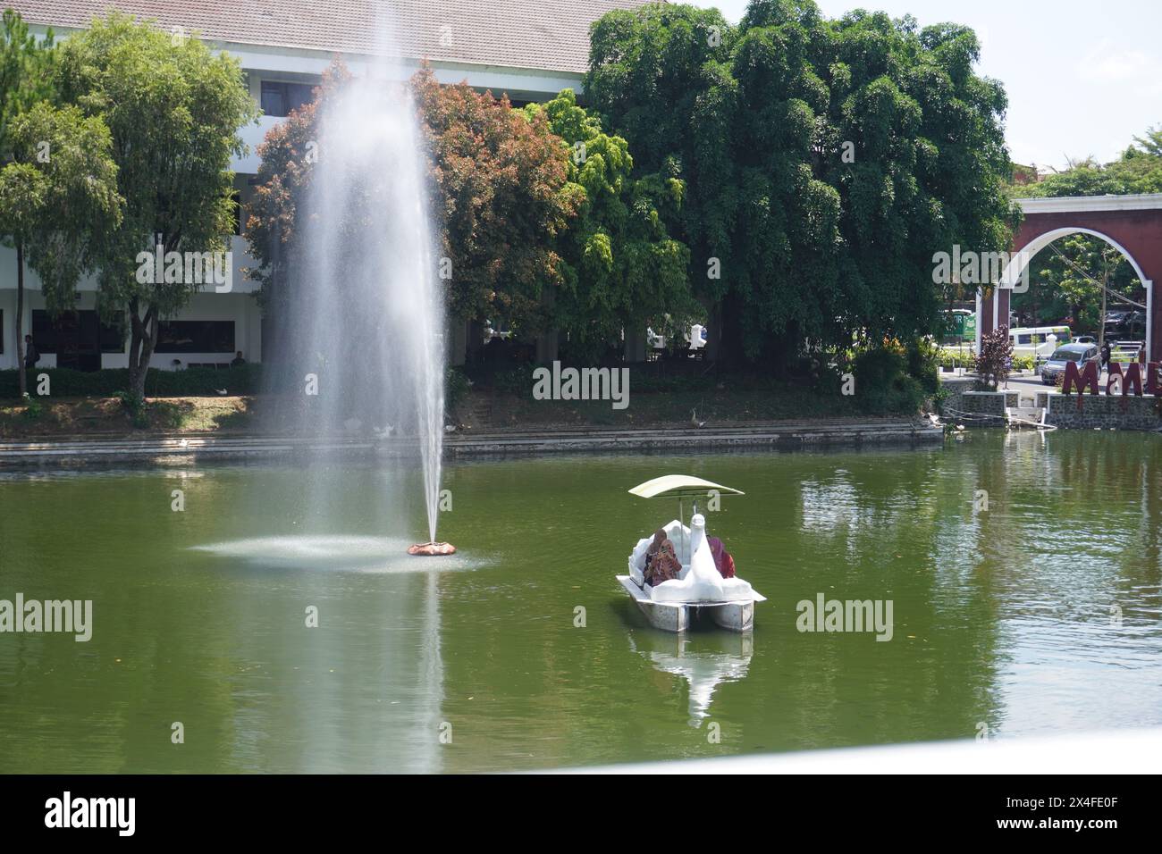 Several women ride a duck boat on an artificial lake with a fountain on a campus Stock Photo