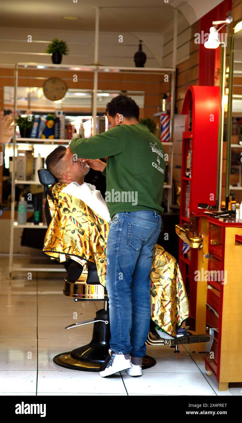 Barber giving haircut to customer inside Stock Photo