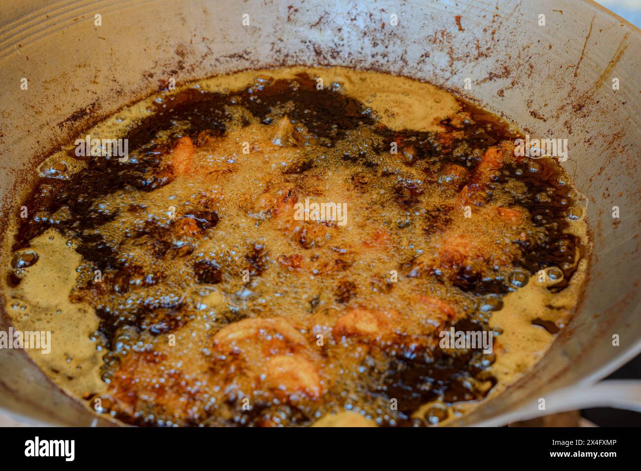 Closeup view of propably crispy fried chicken frying in bubbling hot