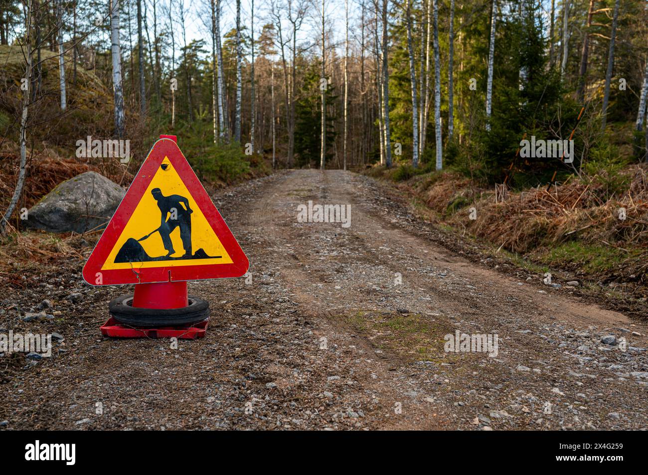 Road work ahead sign on dirt road in forest Motala Sweden April 26 2024 Stock Photo