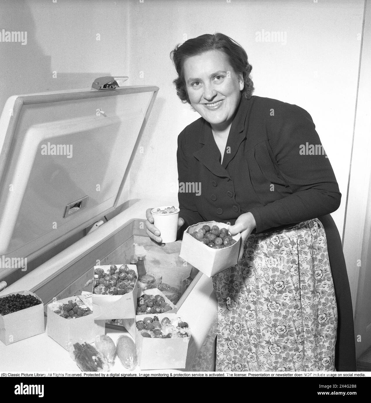 A woman at a freezer with frozen berries and vegetables of different kinds. Deep-frozen food would be the start of a revolution in household habits and food storage. Many were sceptical, and especially canned food manufacturers considered frozen food to be a passing trend.  1952. Conard ref 1978 Stock Photo