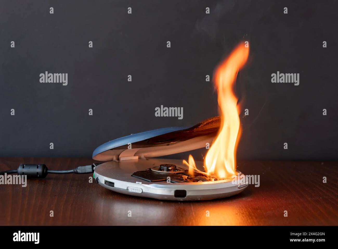The CD player is on fire, connected to the network on the table. The cause of the fire in the apartment is a short circuit. It smoked and caught fire, Stock Photo