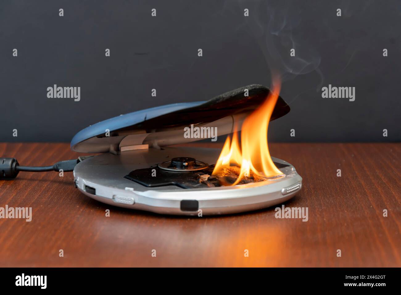 The CD player is on fire, connected to the network on the table. The cause of the fire in the apartment is a short circuit. It smoked and caught fire, Stock Photo
