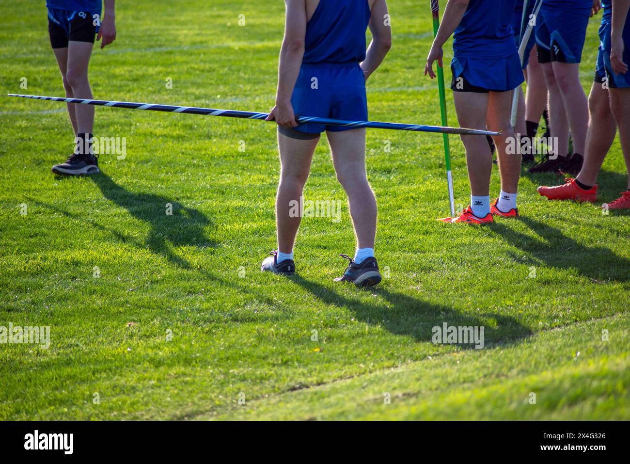 Young track and field athletes in uniform with javelins on grass field Stock Photo