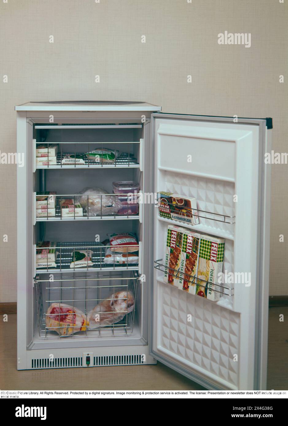 Freezer in the 1970s. A Swedish freezer in a practical cabinet design where four baskets are filled with frozen food. Packaging of Felix cod fillet can also be seen in the door. Deep-frozen food would be the start of a revolution in household habits and food storage. Many were sceptical, and especially canned food manufacturers considered frozen food to be a passing trend. Sweden 1970. ref BV76 Stock Photo