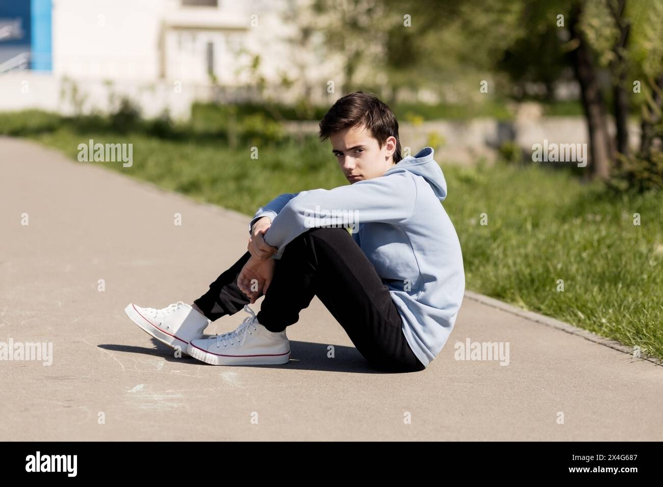 Portrait of adolescent in casual clothes sitting on the ground Stock Photo