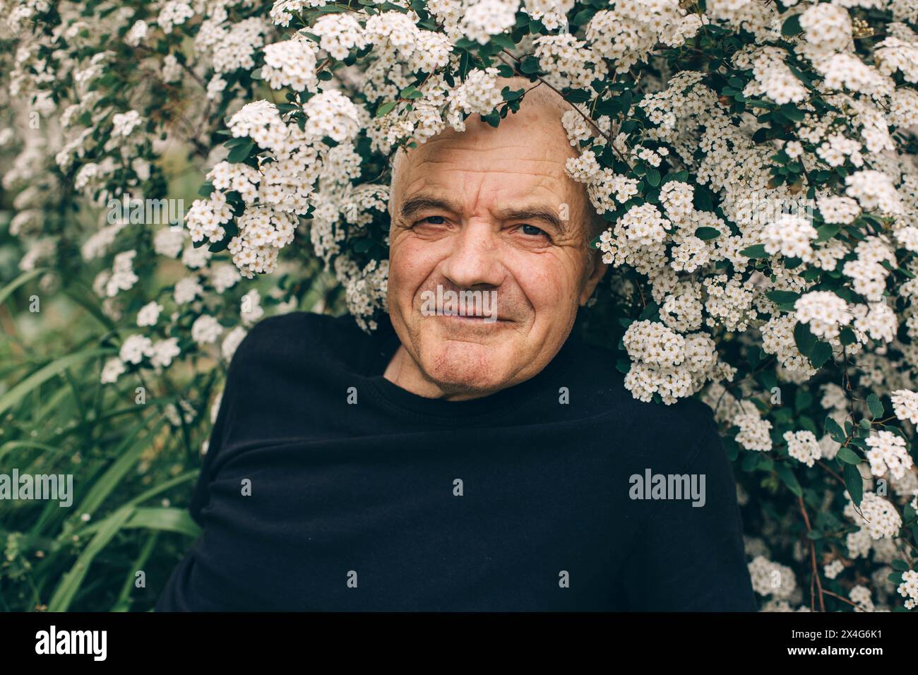 Portrait of happy seniors man in spring flowers Stock Photo