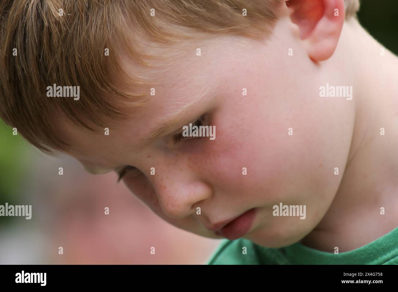 Red-haired boy in deep concentration, immersed in thought Stock Photo