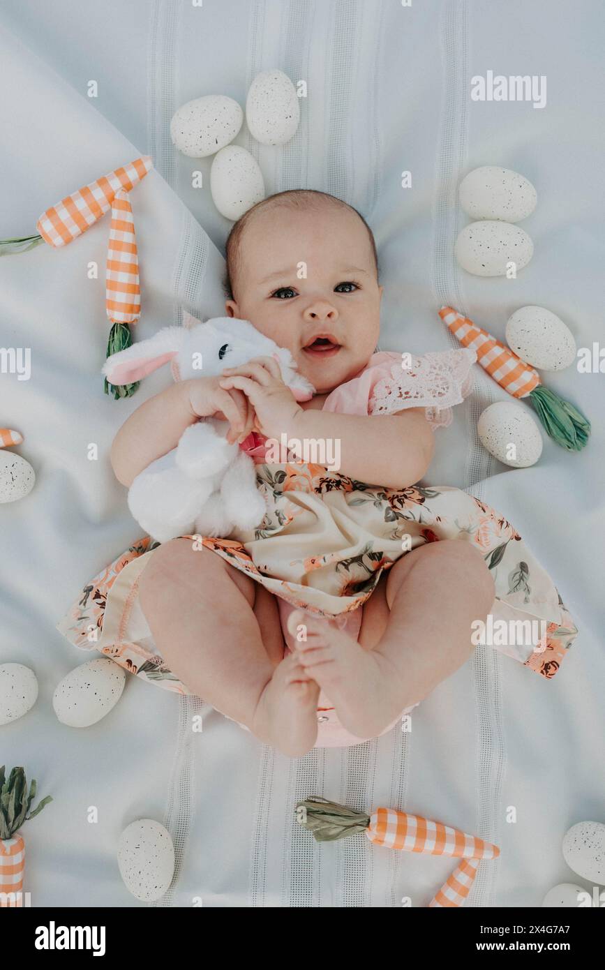 nfant's Easter joy with plush bunny and festive toys Stock Photo