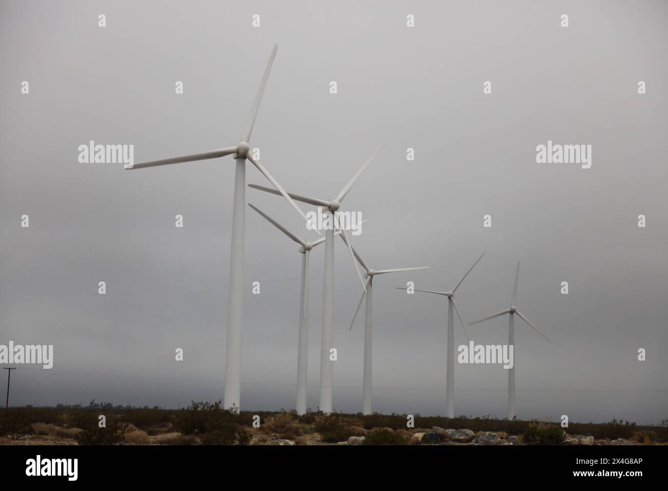 Wind turbines towering over a foggy barren landscape Stock Photo - Alamy
