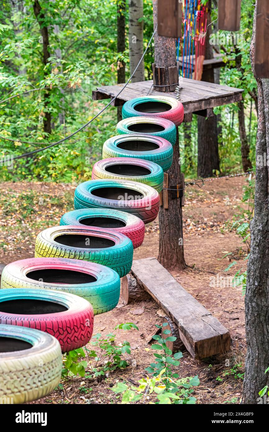Suspended path of multicolor tires linked together between trees in an ...