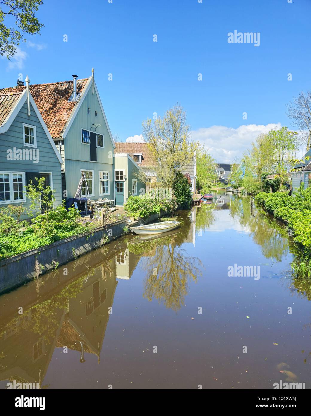 A peaceful river flows through a charming small town, surrounded by traditional houses on either side. Broek in Waterland Netherlands  Stock Photo