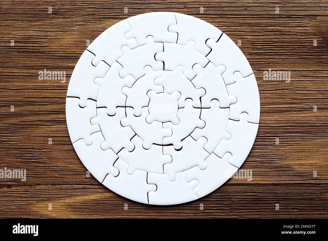 Blank circular jigsaw puzzle arranged on a wooden background with copy space. Stock Photo