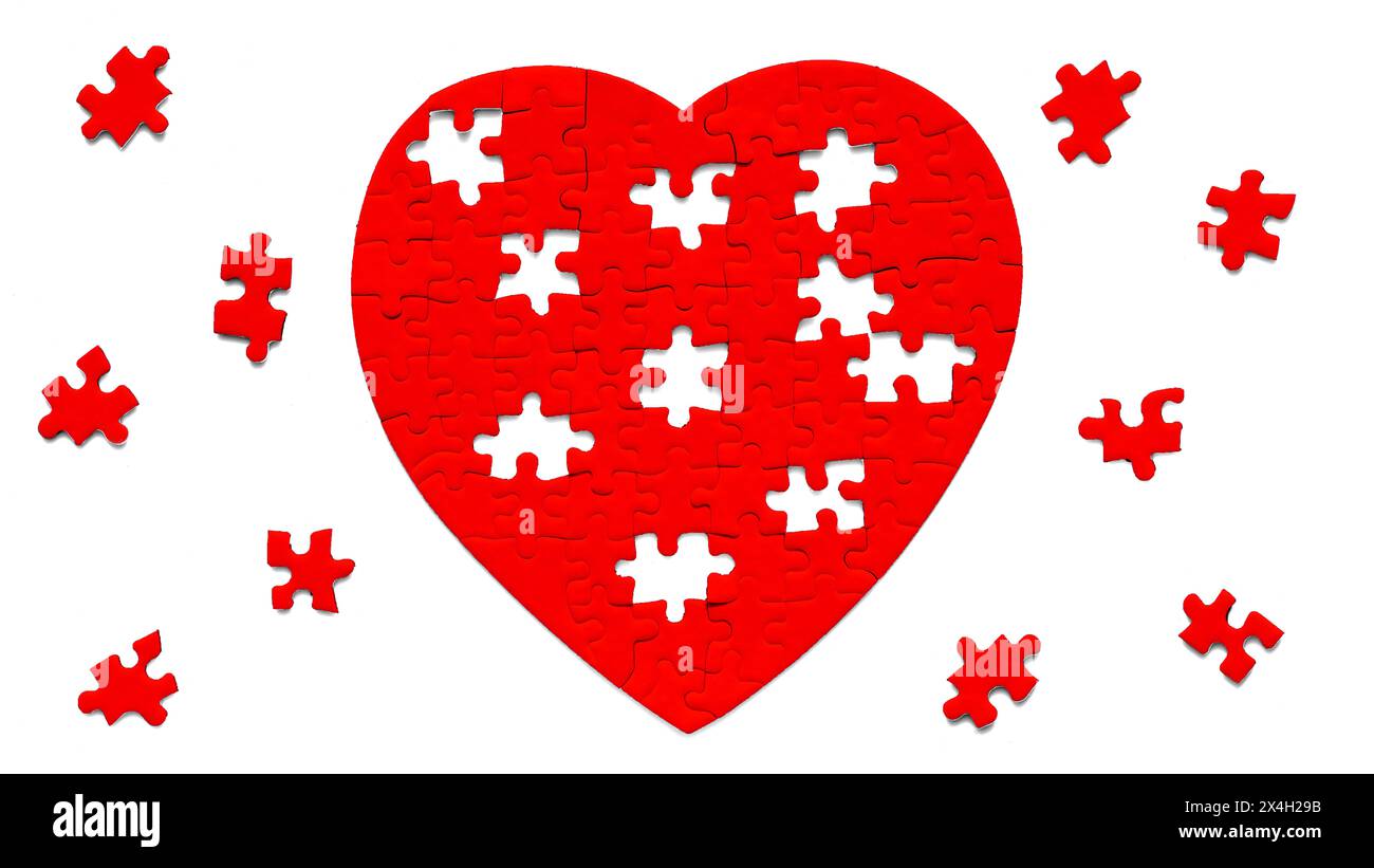 Incomplete red heart-shaped jigsaw puzzle and missing pieces arranged on a serene white backdrop. Love and unity related concept. Stock Photo