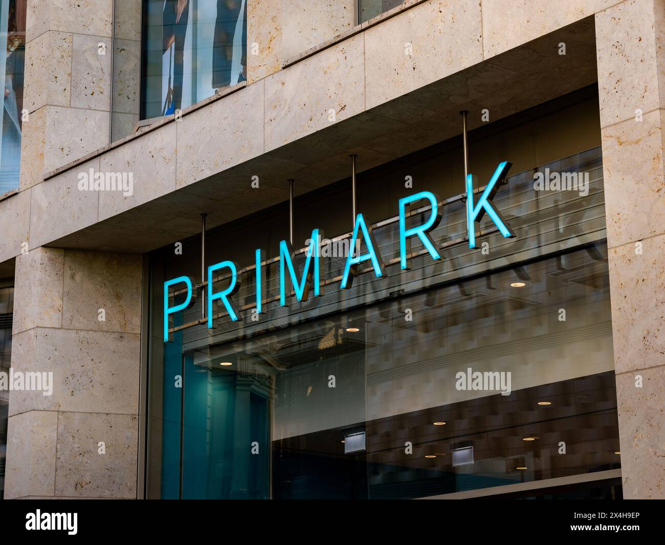 Primark logo sign of the discount fashion chain. Illuminated logotype over a building entrance. Retailer for fast fashion and employer in the city. Stock Photo