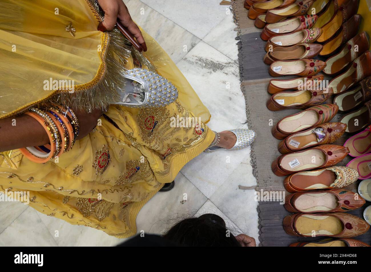 Beautiful Indian Rajasthani woman trying out her foot for fitting of colorful Rajsathani ladies shoes at shoe store at famous Sardar Market. Stock Photo