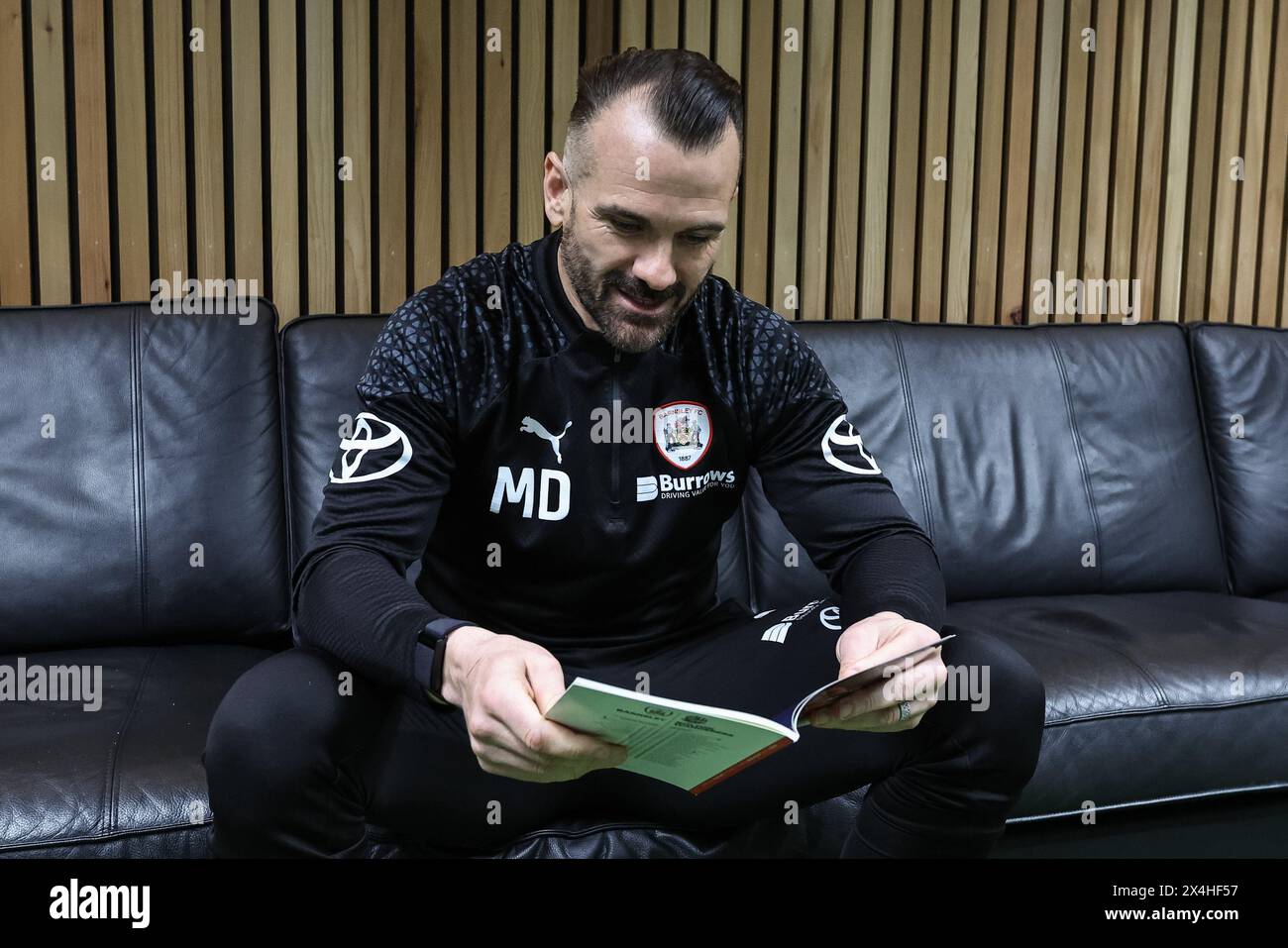 Martin Devaney caretaker manager of Barnsley reading todays match day program during the Sky Bet League 1 Promotion Play-offs Semi-final first leg match Barnsley vs Bolton Wanderers at Oakwell, Barnsley, United Kingdom, 3rd May 2024  (Photo by Mark Cosgrove/News Images) Stock Photo