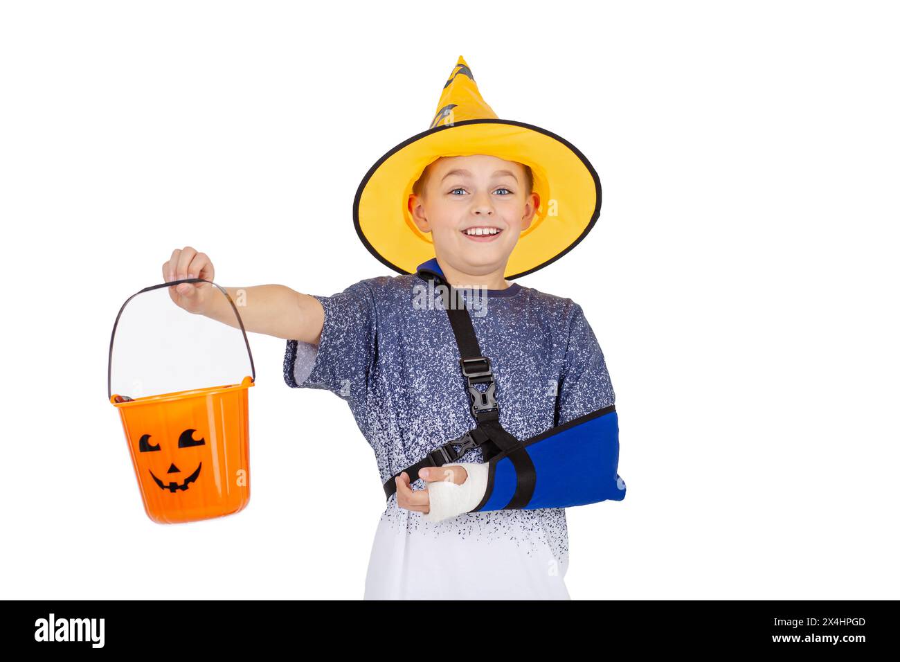 Young boy in a wizard hat and sparkly cape, smiling with a Halloween bucket, ready for trick-or-treating Stock Photo