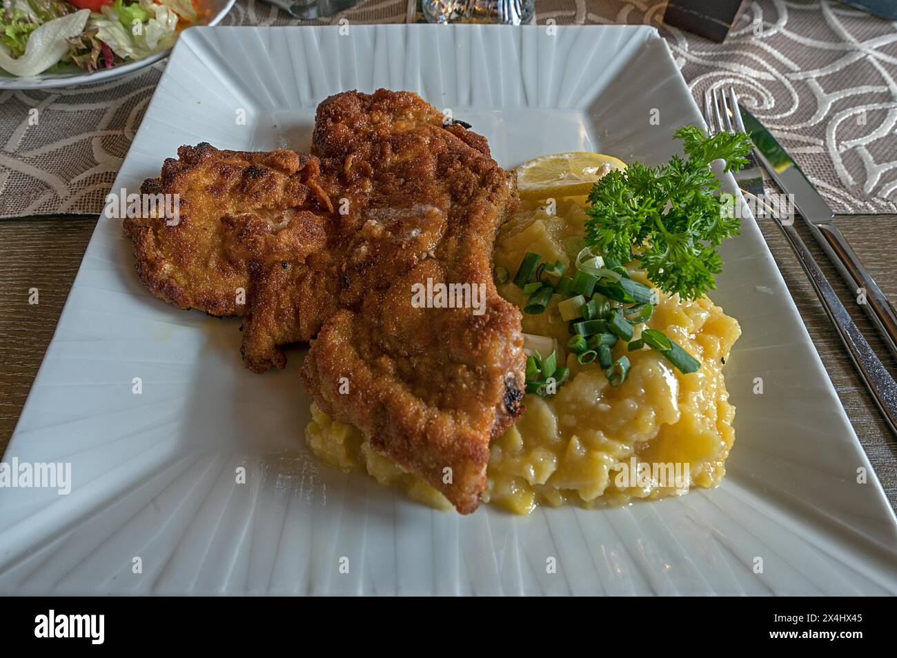 Baked pork chop with potato salad served in a pub, Franconia, Bavaria, Germany Stock Photo