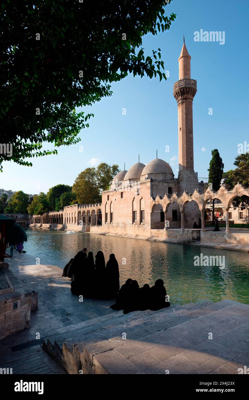 Muslim women wearing abaya in front of Abraham's Pool where the prophet was thrown into fire by King Nimrod, Sanliurfa, Turkey Stock Photo