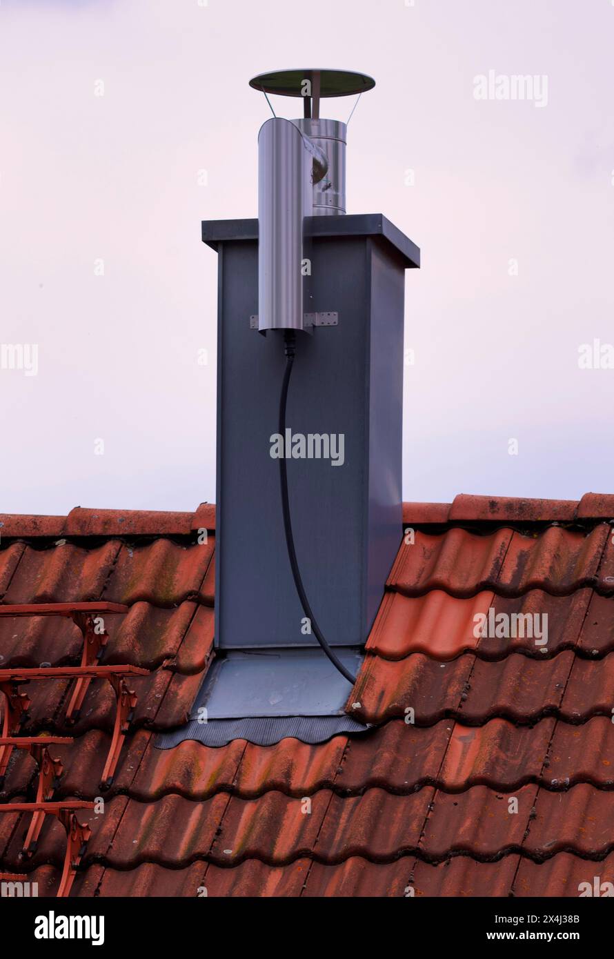 Retrofitted chimney on roof, with dust separator, electrostatic filtering of soot particles from the inside of the flue pipe, power connection Stock Photo