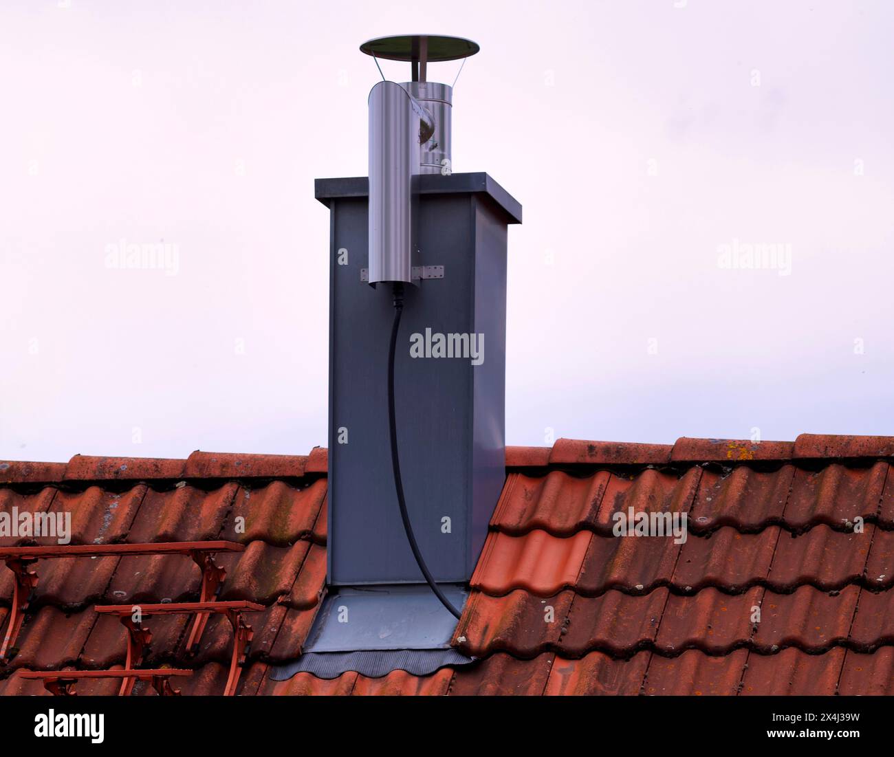 Retrofitted chimney on roof, with dust separator, electrostatic filtering of soot particles from the inside of the flue pipe, power connection Stock Photo