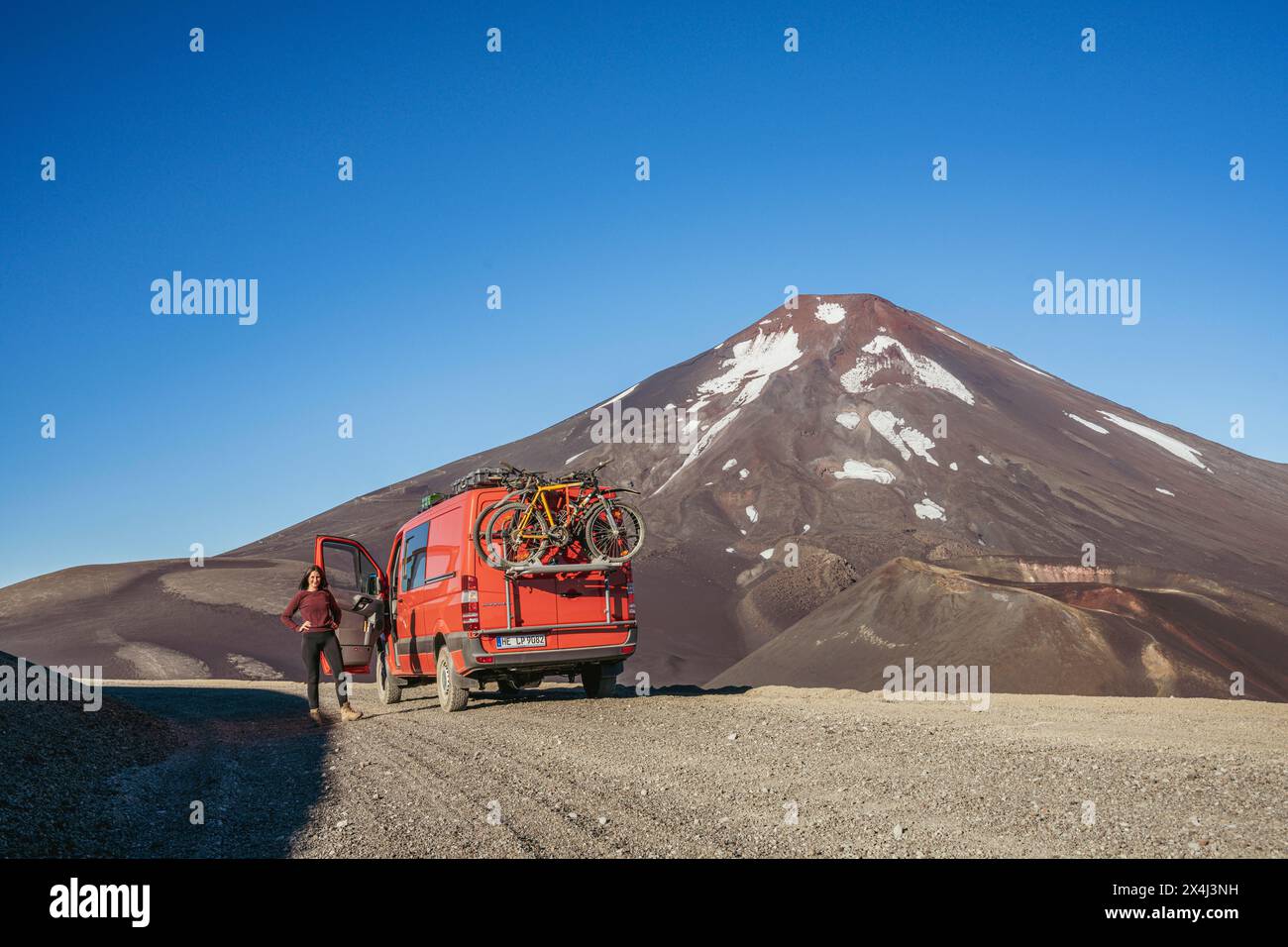 Young woman and her campervan in front of the Lonquimay volcano, Lonquimay volcano, Malalcahuello National Reserve, Curacautin, Araucania, Chile Stock Photo