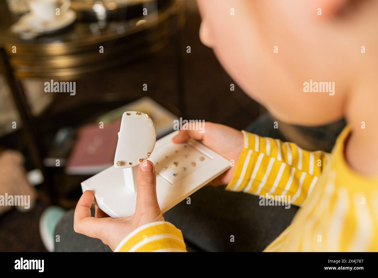 Over-the-shoulder view of a child holding earring display in a jewelry store in a jewelry store Stock Photo