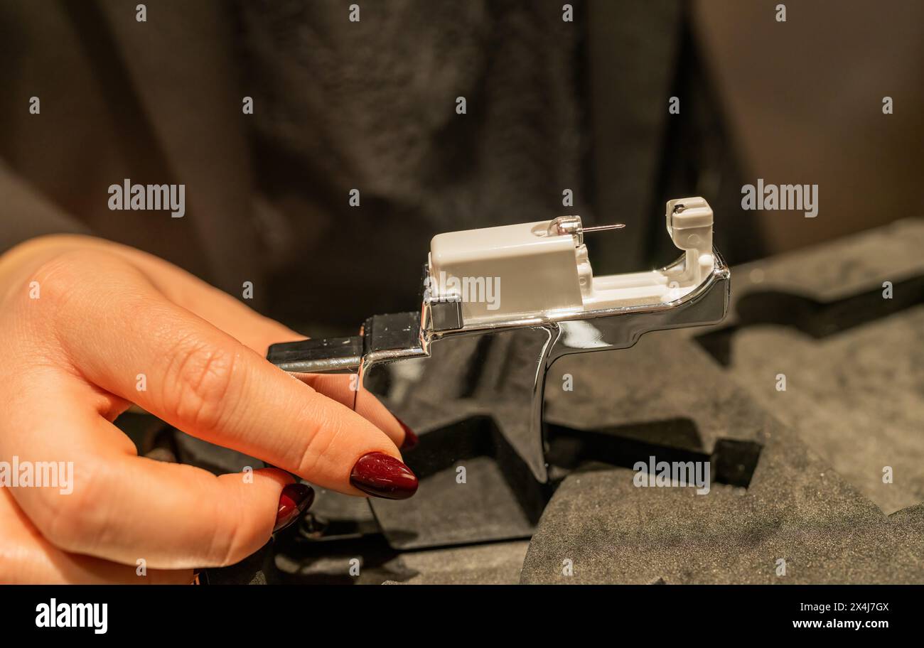 hand holding an ear piercing gun in a jewelry store, preparing for an