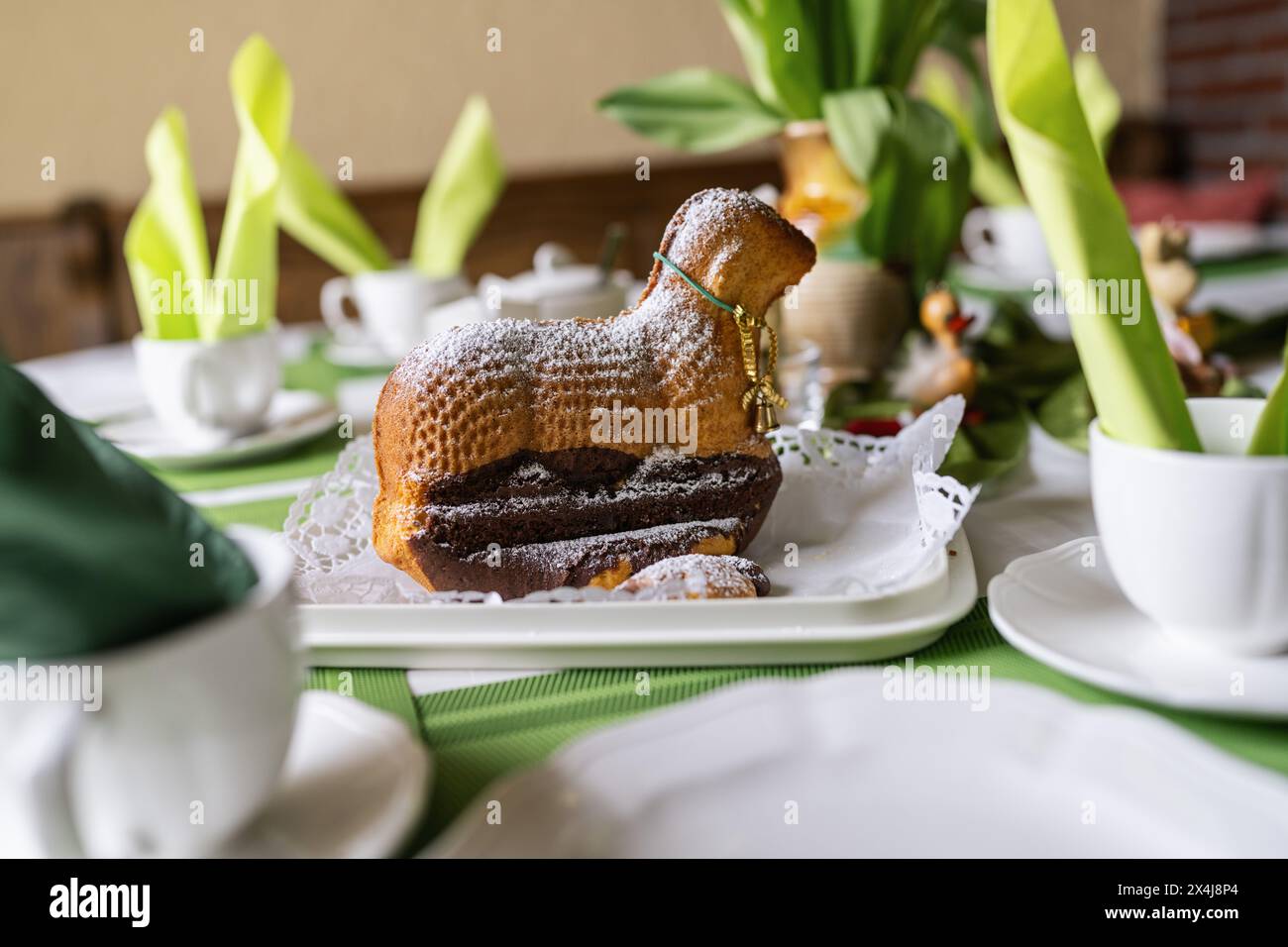 Easter cake shaped like a lamb, dusted with powdered sugar, on a festive table setting Stock