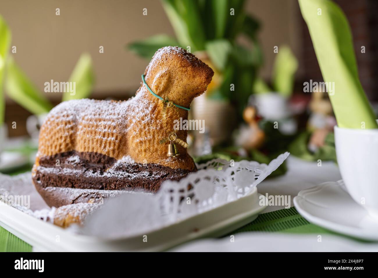 Close-up of a lamb-shaped Easter cake with sugar dusting on a decorated table. Stock Photo