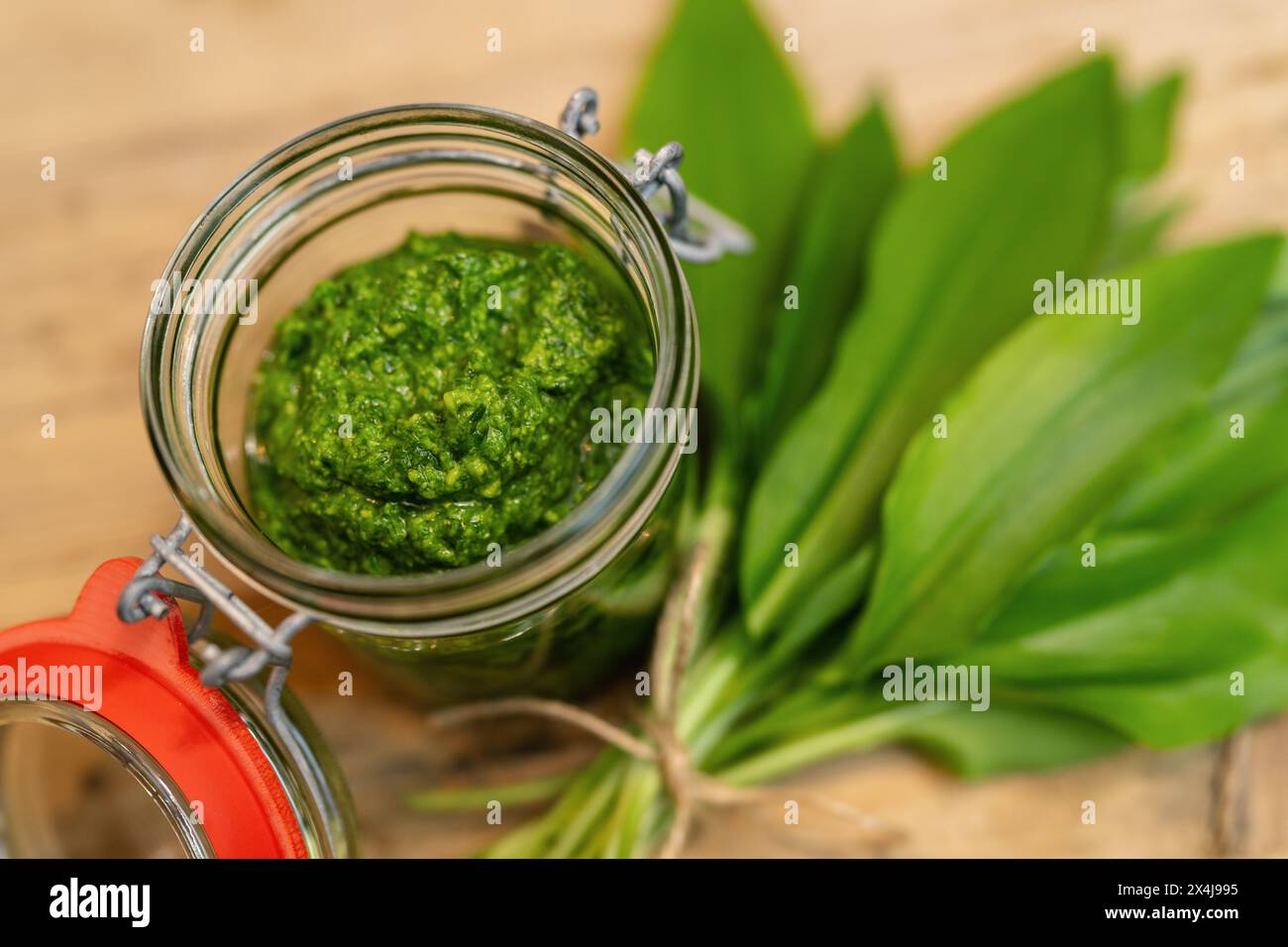 open jar with wild garlic pesto and fresh wild garlic leaves on wood Stock Photo