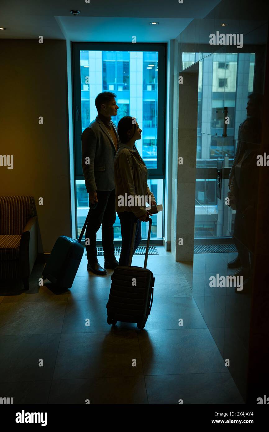 Tourist couple standing in hallway in front of elevator doors Stock Photo